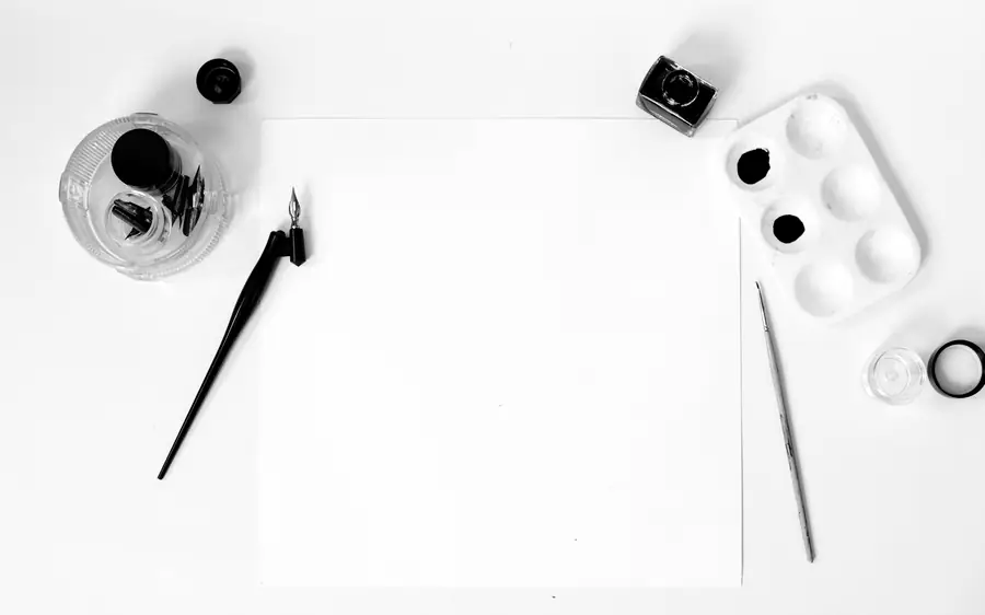 A blank sheet of paper with ink, pens and a brush laid around it