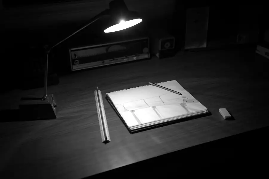 A desk lamp lighting a drawing board in a dark room