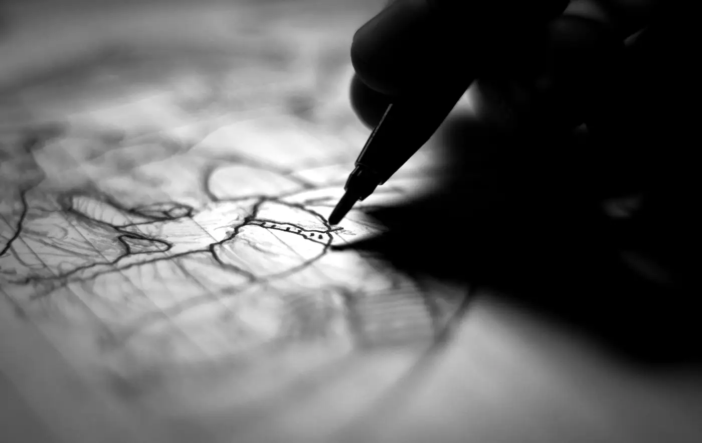 A pen drawing lines on paper, photographed in black and white