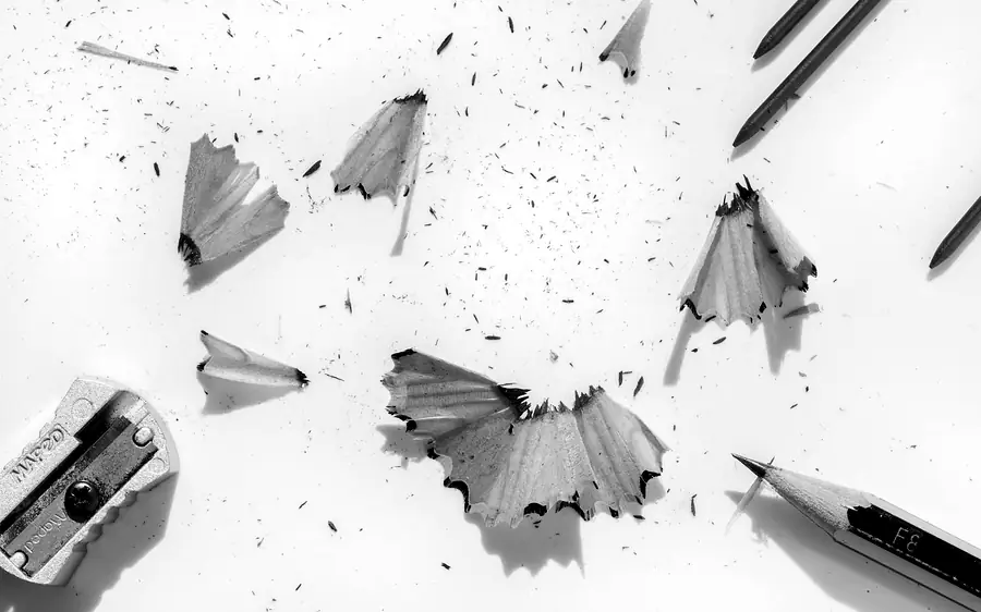 Pencil shavings scattered on white paper beside a sharpener