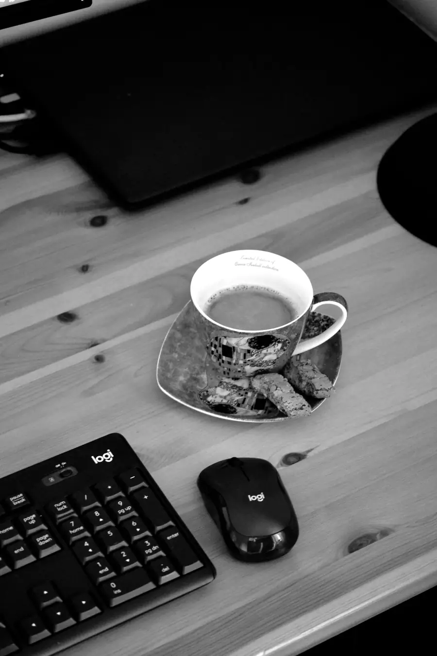 A cup of tea on a wooden desk next to biscuits
